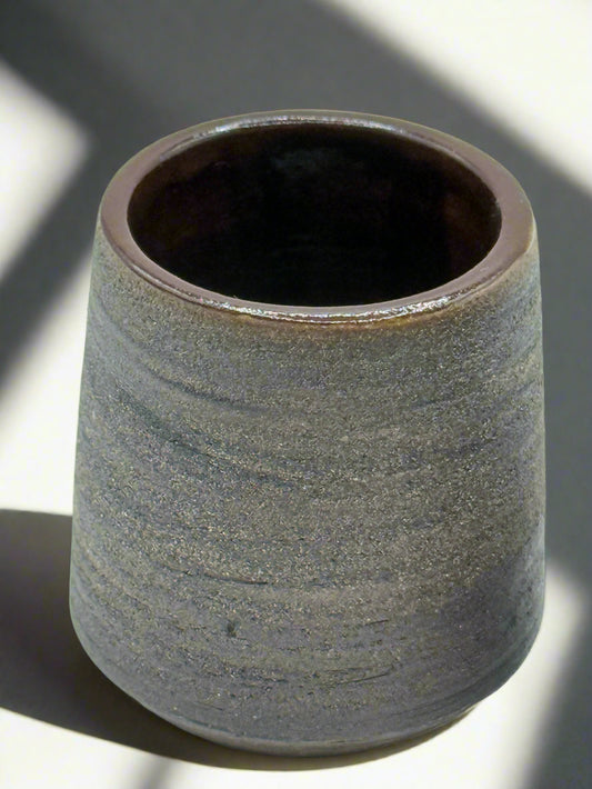 Cylindrical ceramic cup with textured surface on a white background