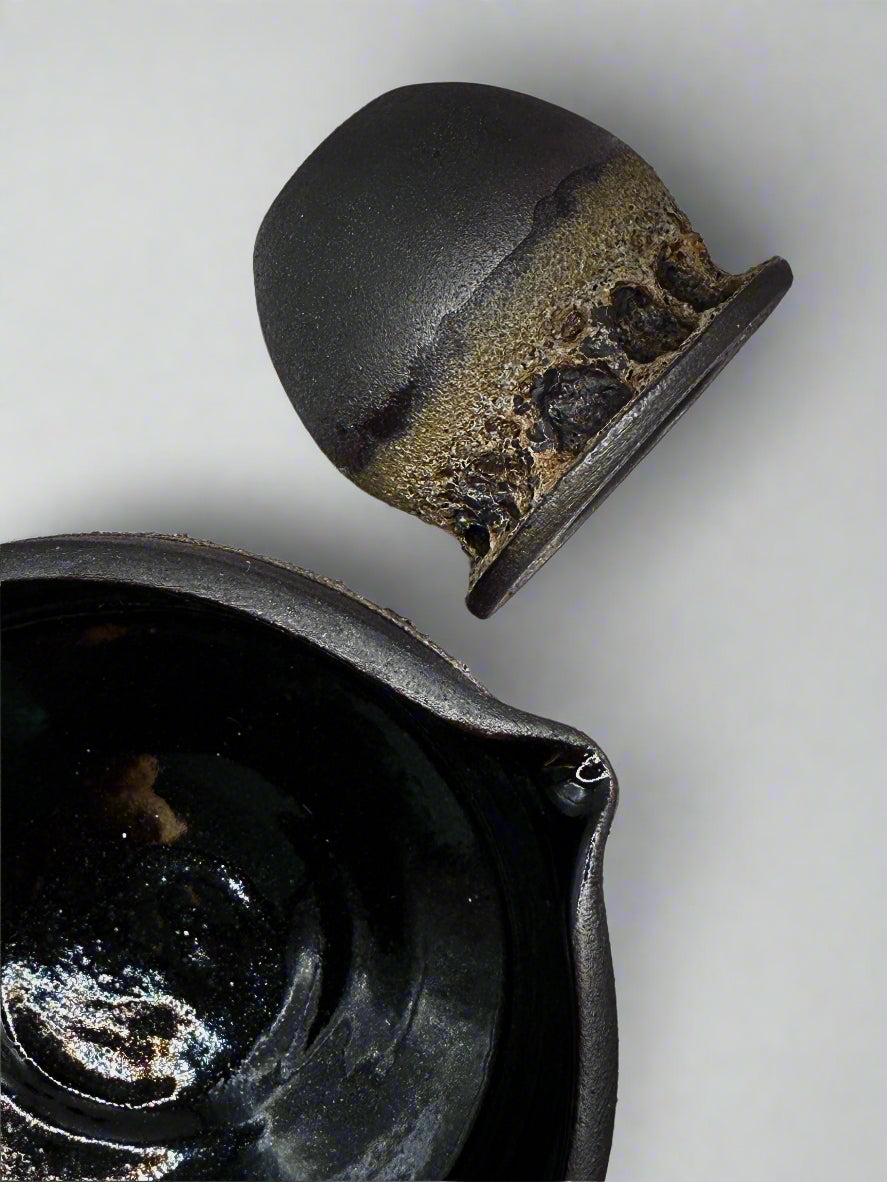 Close-up of a black ceramic matcha bowl with a whisk holder