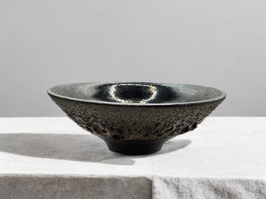 Black ceramic bowl on a light gray surface with a neutral background
