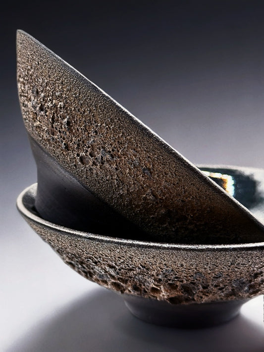 Black ceramic bowl with textured exterior on a gradient background