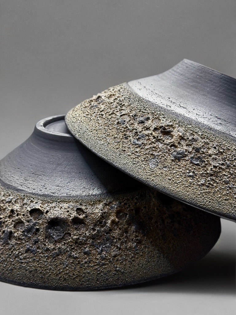 Two ceramic bowls with textured surfaces on a gray background