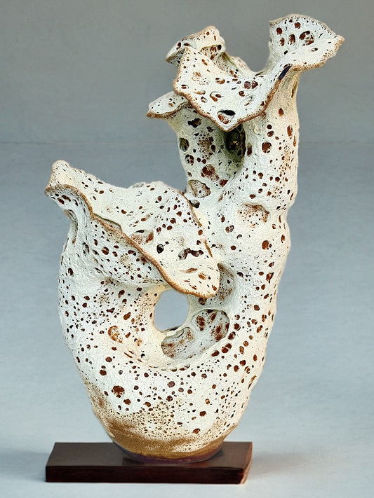 Hand-built ceramic sculpture with flowing, organic folds and cratered textures, made from red stoneware and fired to 1280°C.