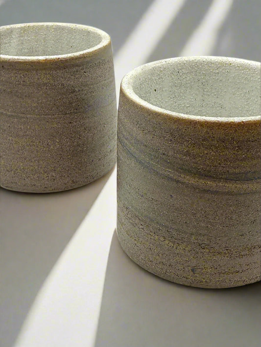 Two ceramic cups with a textured surface on a white background