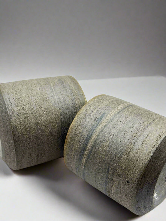 Two cylindrical ceramic objects with a textured surface on a white background