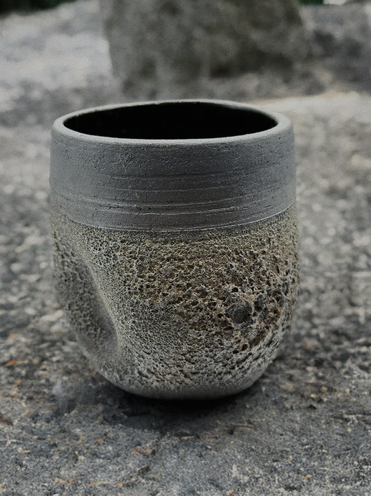 Textured stone cup on a stone surface